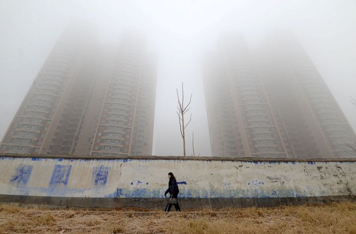 12 Ιανουαρίου 2019, Χαντάν - Κίνα. Μία γυναίκα με μάσκα στο πρόσωπο περπατάει ανάμεσα σε κτίρια μία ημέρα όπου καταγράφεται αυξημένη ποσότητα ρύπων στην ατμόσφαιρα. Όλα αυτά, προ κορονοϊού... REUTERS/Stringer/File Photo