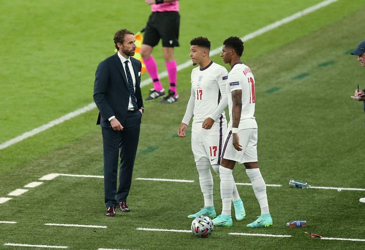 England players Jadon Sancho and Marcus Rashford on the pitch with coach Gareth Southgate