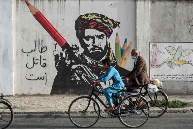 Cyclist peddles past a mural painted on the wall along a road in Kabul on July 11, 2021. (Photo by SAJJAD...