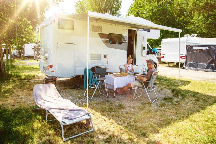 Pareja comiendo fuera de su autocaravana.