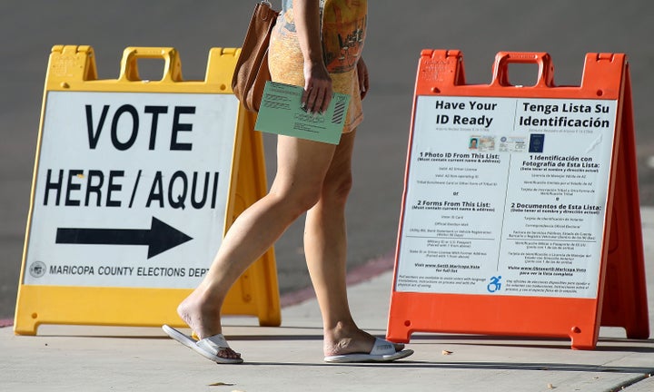 An Arizona voter carries her ballot to a Phoenix polling place to vote in the state's primary on Aug. 28, 2018. Arizona has a