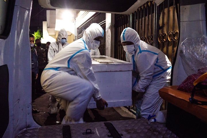 Members of the volunteer police carried a coffin into an ambulance following the suspected COVID-19 death of a man in self-is