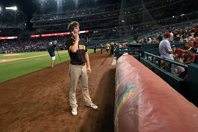 San Diego Padres' Wil Myers talks on a cell phone during a stoppage in play due to an incident near the ballpark during the sixth inning of a baseball game Saturday, July 17, 2021, in Washington. (AP Photo/Nick Wass)