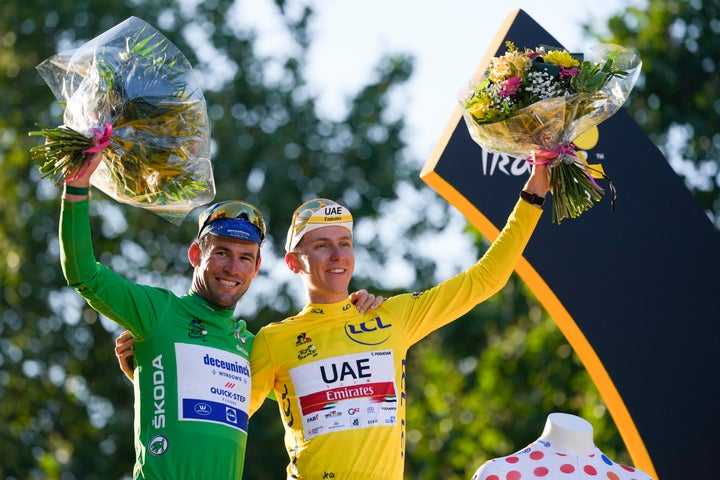 Tadej Pogacar, who won the yellow jersey of the overall leader, the best climber's dotted jersey and the best young rider's white jersey, celebrates with Britain's Mark Cavendish, who's seen wearing the best sprinter's green jersey.