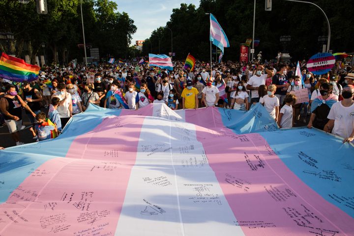 スペイン・マドリードで開かれたプライドパレードで、トランスジェンダーフラッグを広げて囲む人々（2021年7月3日）