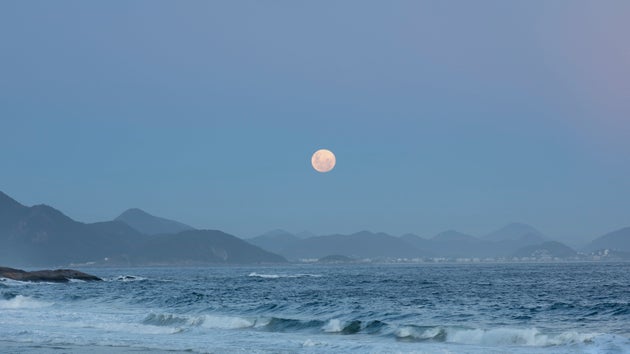 Rio de Janeiro, Brazil - February 8, 2020:  View of the full moon rising above the mountain range landscape.