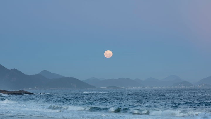 Rio de Janeiro, Brazil - February 8, 2020: View of the full moon rising above the mountain range landscape.