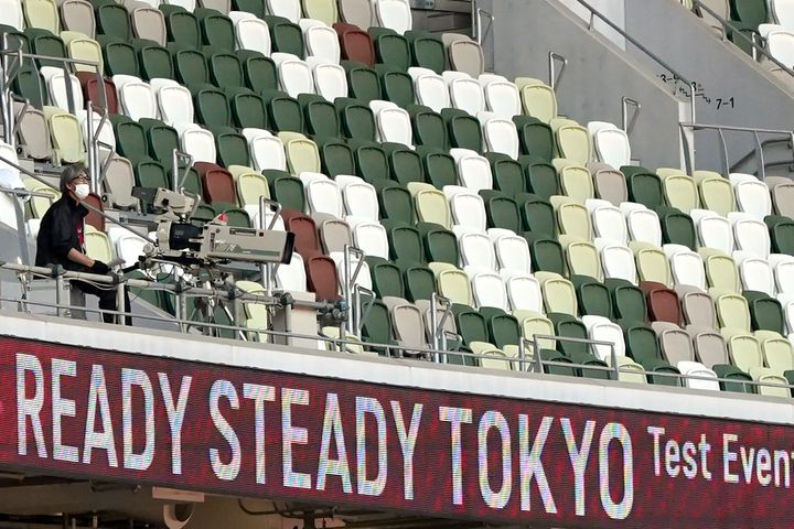 A TV cameraman sits beside empty spectators' seats during an athletics test event for Tokyo 2020 Olympics Games at the Nation