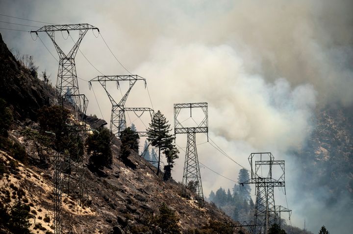 Smoke billows behind power lines as the Dixie Fire burns along Highway 70 in Plumas National Forest, Calif., on Friday, July 16, 2021. (AP Photo/Noah Berger)