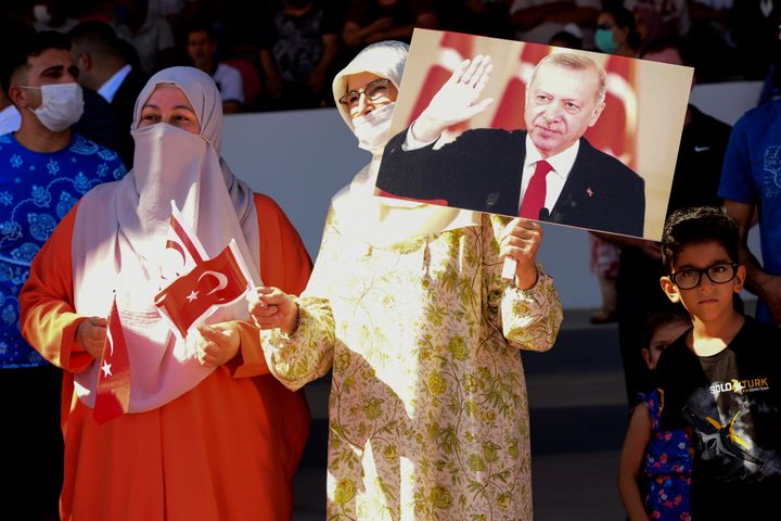 20 Ιουλίου 2021, κατεχόμενη Κύπρος. Ο Ταγίπ Ερντογάν διακηρύσσει ότι μόνο με διχοτόμηση θα βρεθεί λύση στο Κυπριακό, ενώ δύο μαντηλοφορούσες τον παρακολουθούν με θαυμασμό. (AP Photo/Nedim Enginsoy)