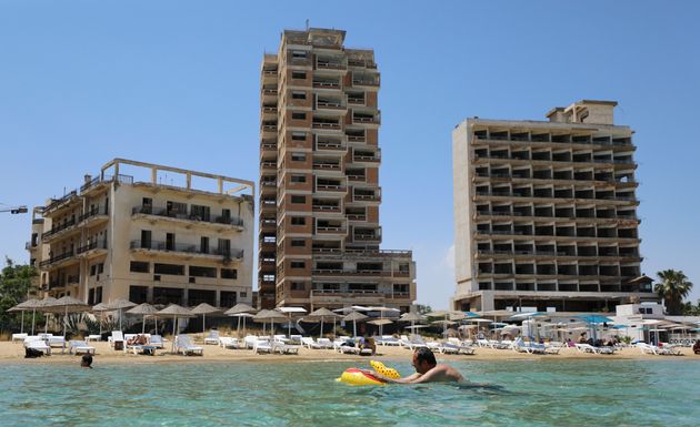 Εικόνα από το σουρεαλιστικό σκηνικό έμπνευσης Ερντογάν στα Βαρώσια. Κολυμβητές και ομπρέλες στην παραλία μπροστά σε έρημα ξενοδοχεία που ανήκουν σε Ελληνοκυπρίους οι οποίοι έχουν χάσει την πρόσβαση στις περιουσίες τους. (Photo by Danil Shamkin/NurPhoto via Getty Images)