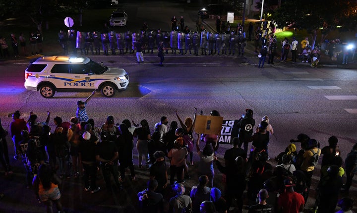 Protesters are seen as police officers stand guard during protest against police brutality and the arrest of two brothers Ric