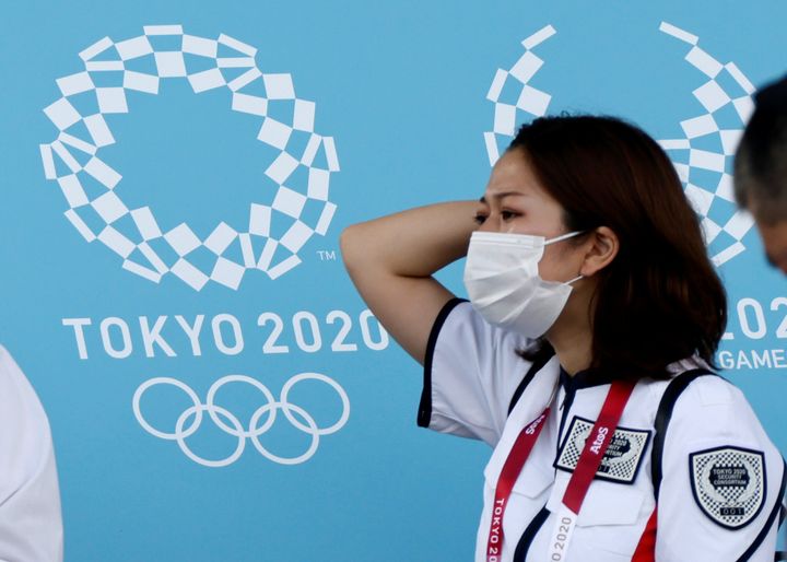 10 Ιουλίου 2021. Μία γυναίκα από το προσωπικό ασφαλείας των Ολυμπιακών Αγώνων Τόκιο 2020 στέκεται δίπλα στο λογότυπο της διοργάνωσης. Η μάσκα στα απολύτως απαραίτητα 2021. REUTERS/Fabrizio Bensch