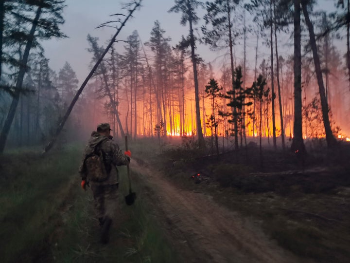 In this Saturday, July 17, 2021 photo, a volunteer walks to douse a forest fire in the republic of Sakha also known as Yakutia, Russia Far East.