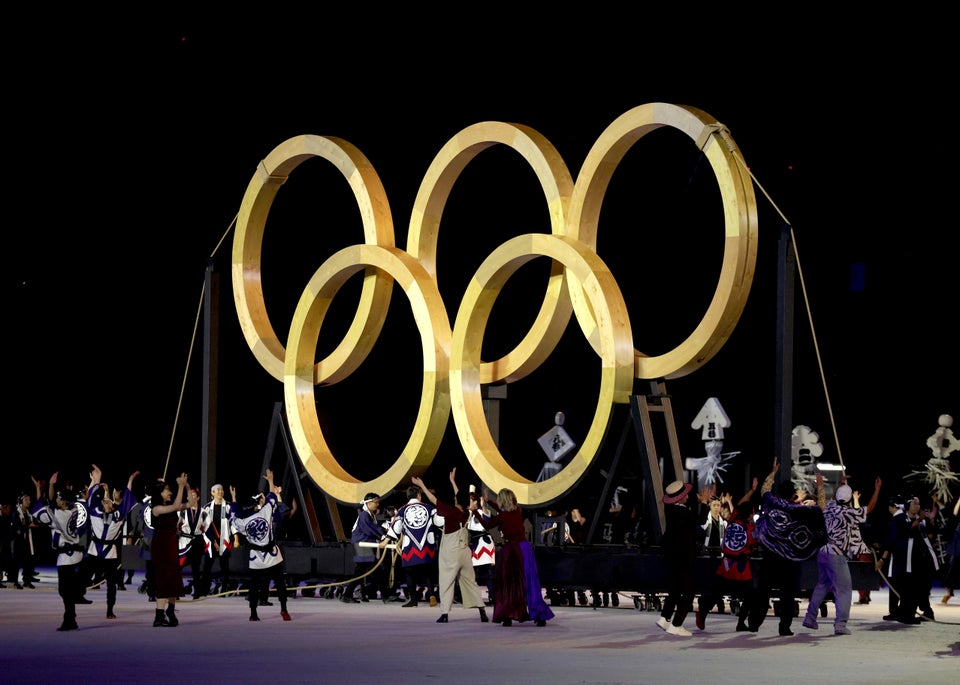Performers dance in front of giant golden Olympic