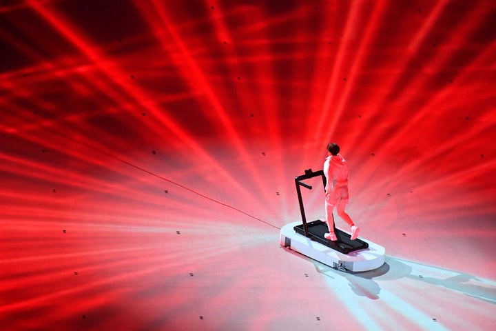 An overview shows a performer on a treadmill during the opening ceremony.