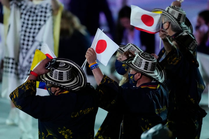 Colombian athletes wave Japanese flags as they enter the stadium.