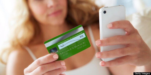 Woman using smart phone mobile device with credit card to make online purchase.