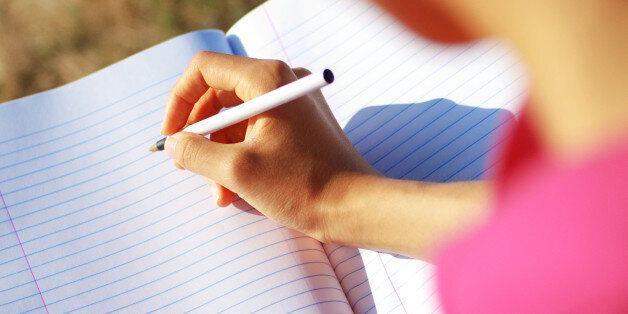 Girl writing in notebook in a field.