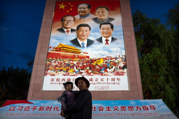 A man holds a girl as they pose for a photo in front of a large mural depicting Chinese President Xi Jinping, bottom center, and other Chinese leaders at a public square at the base of the Potala Palace in Lhasa in western China's Tibet Autonomous Region on June 1, 2021. Chinese leader Xi Jinping has made a rare visit to Tibet as authorities tighten controls over the Himalayan region’s traditional Buddhist culture, accompanied by an accelerated drive for economic development and modernized infrastructure. (AP Photo/Mark Schiefelbein)