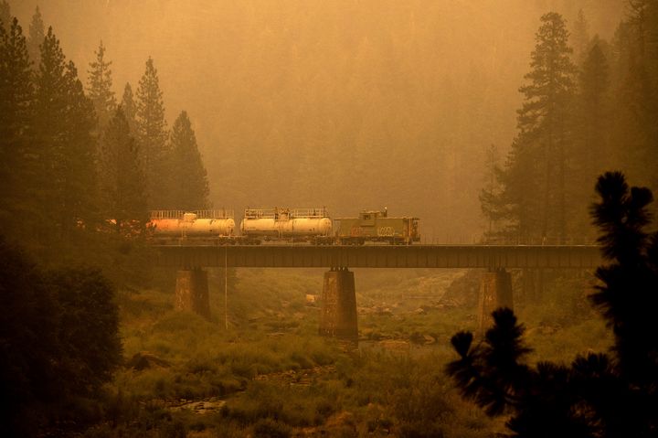 A fire train crosses a bridge as the Dixie Fire burns in Plumas County, Calif., on Saturday. The train is capable of spraying retardant to coat tracks and surrounding land.