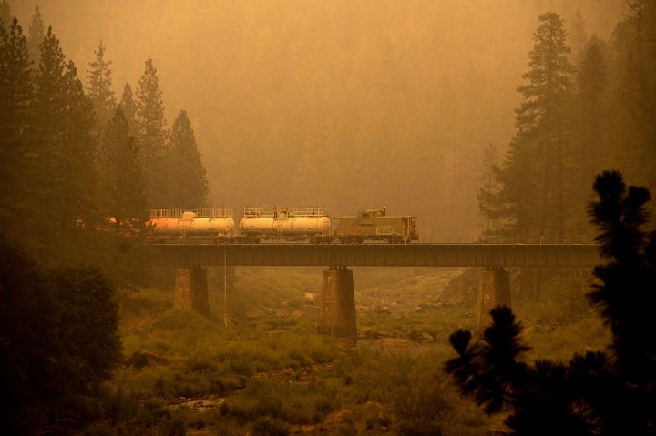 A fire train crosses a bridge as the Dixie Fire burns in Plumas County, Calif., on Saturday. The train is capable of spraying