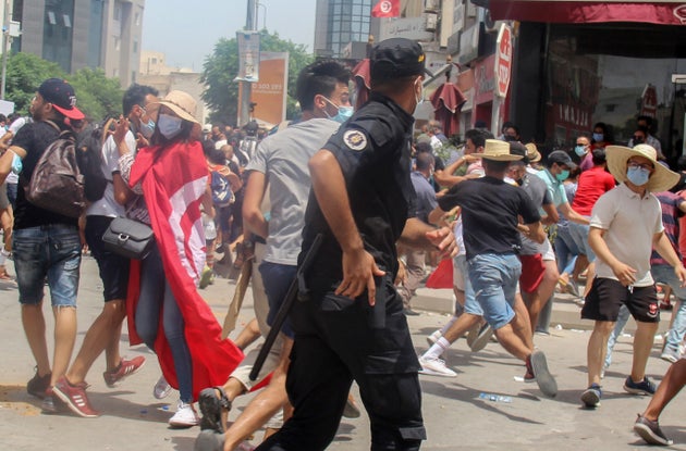 A Tunisian police officer scuffles with protesters during a demonstration in Tunis, Tunisia, Sunday, July 25, 2021. Violent demonstrations broke out on Sunday in several Tunisian cities as protesters expressed anger at the deterioration of the country's health, economic and social situation. (AP Photo/Hassene Dridi)