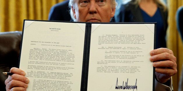 U.S. President Donald Trump holds up a signed executive order to advance construction of the Dakota Access pipeline at the White House in Washington January 24, 2017. REUTERS/Kevin Lamarque