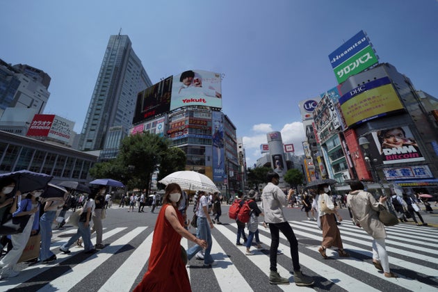 People wearing face masks to help curb the spread of the coronavirus walk across a busy crossing at Shibuya district in Tokyo Saturday, July 24, 2021, a day after the opening of the Tokyo Olympics. (AP Photo/Kantaro Komiya)