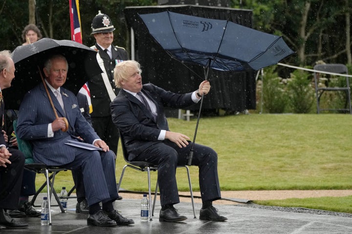 British Prime Minister Boris Johnson tries to open his umbrella next to Prince Charles at the dedication ceremony of the new