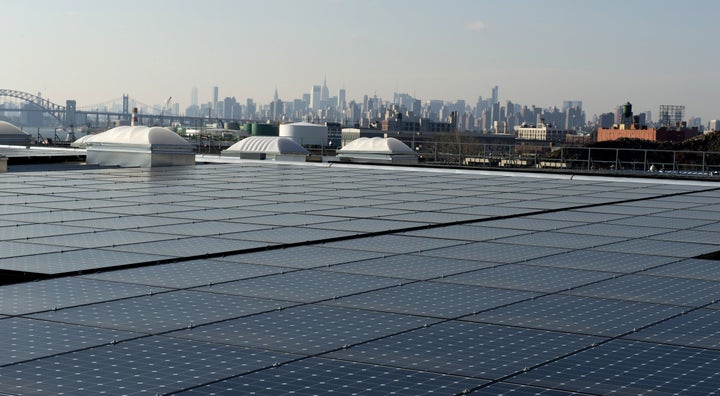 The New York City skyline unfolds behind solar panels atop a restaurant in the northernmost borough of The Bronx.