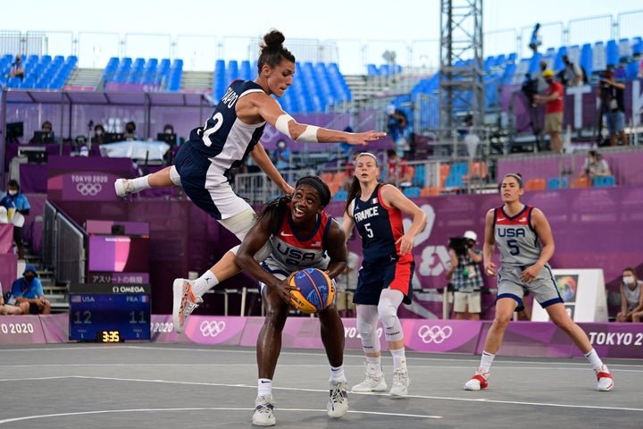 With almost no audience to cheer them on, France's Laetitia Guapo, left, fights for the ball with Team USA's Jacquelyn Young, center, during the women's semifinal 3x3 basketball match on July 28, 2021.