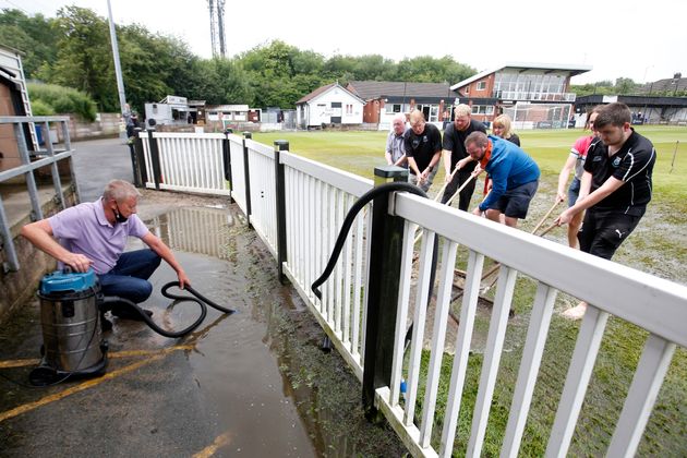 Staff work on a waterlogged pitch before a cricket game at Sir Tom Finney Stadium in Blackburn on July 10