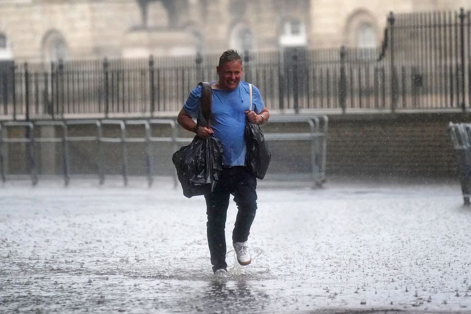 A man walks through water in Horse Guards Road on July 25