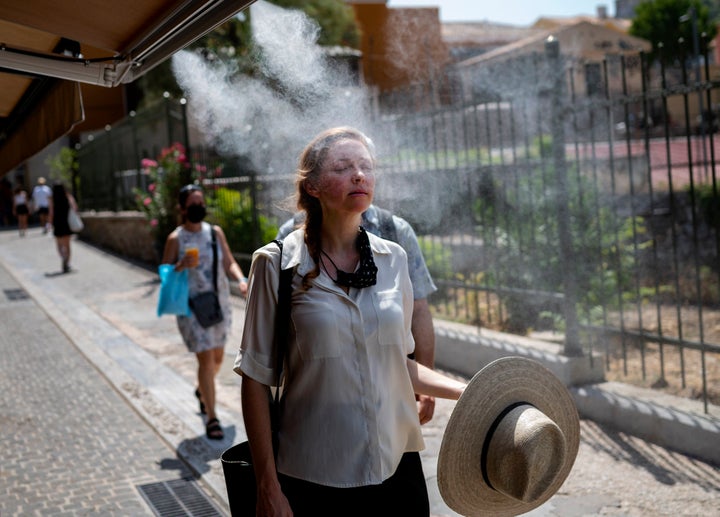 Τουρίστρια στο ιστορικό κέντρο της Αθήνας δροσίζεται από το σπρέι νερού καφετέριας. 