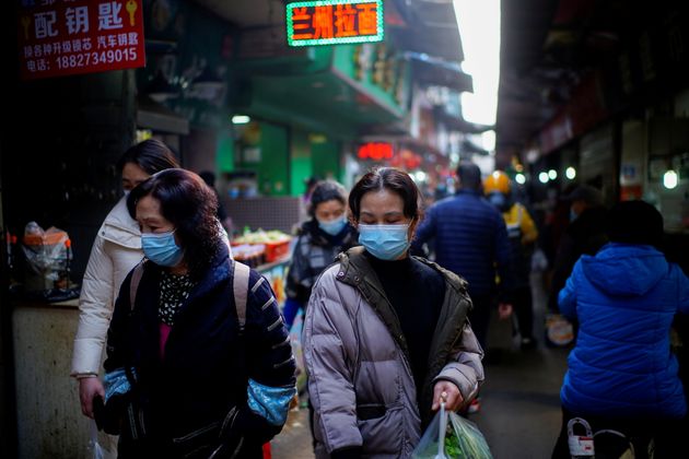 Des passants dans un marché de Wuhan, le 8 février 2021