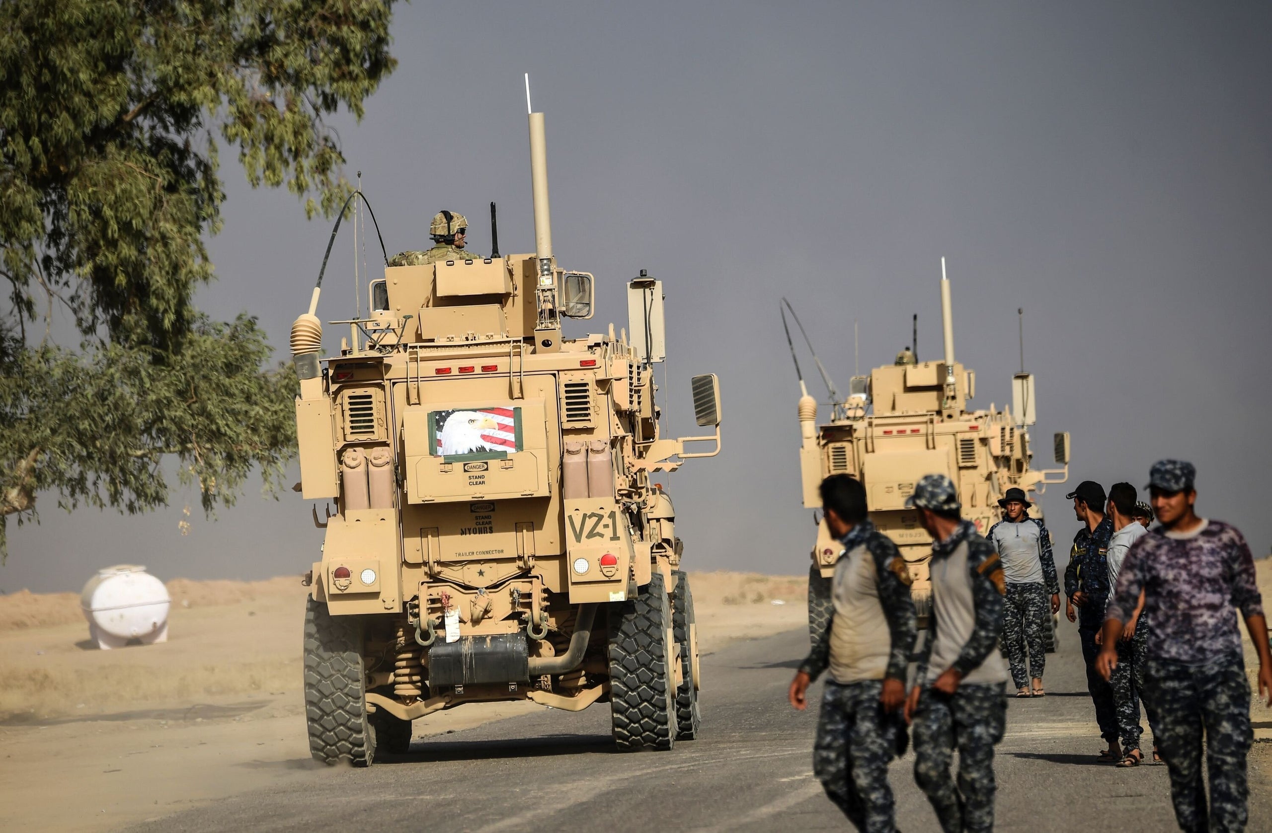 Members of Iraqi forces walk near an MRAP used by US forces supporting the operation to recapture Mosul from the Islamic Stat