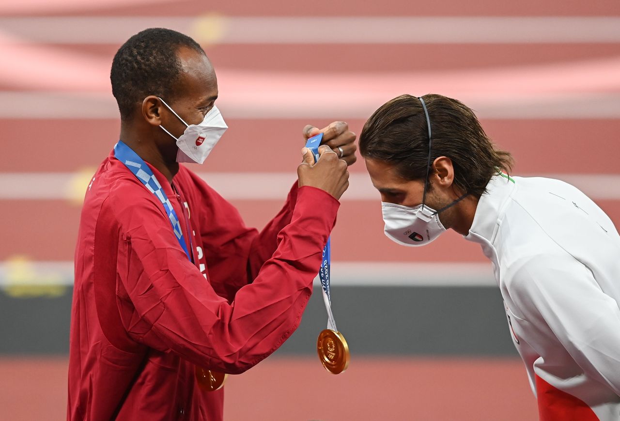 Gold medalist Mutaz Essa Barshim of Qatar, left, presents Gianmarco Tamberi of Italy with his gold medal during the men's high jump medal ceremony at the Olympic Stadium on Day 10 of the 2020 Tokyo Summer Olympic Games in Tokyo, Japan. The two athletes decided to share the gold medal after both ended the event with jumps of 2.37 meters.