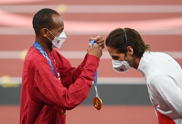 Gold medalist Mutaz Essa Barshim of Qatar, left, presents Gianmarco Tamberi of Italy with his gold medal during the men's high jump medal ceremony at the Olympic Stadium on Day 10 of the 2020 Tokyo Summer Olympic Games in Tokyo, Japan. The two athletes decided to <a href=