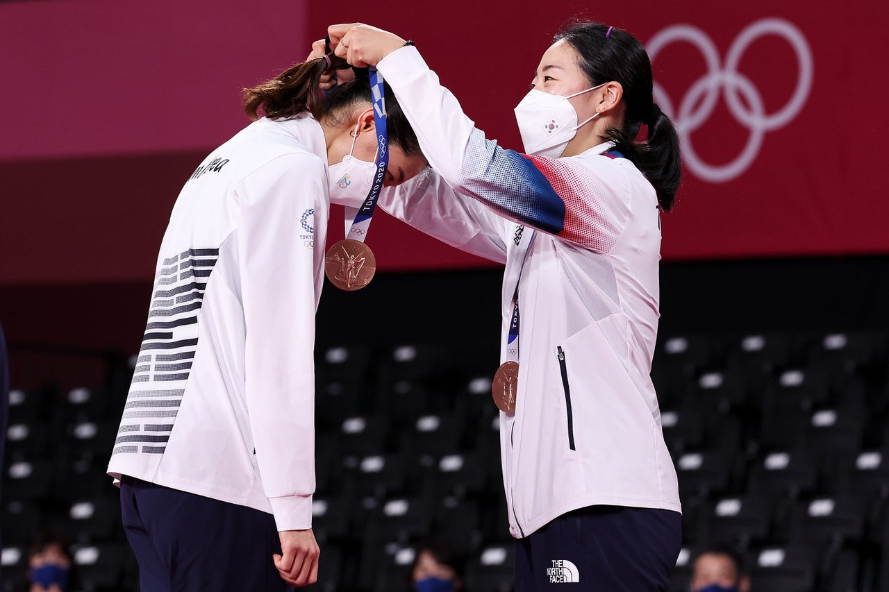 Bronze medalists Kim Soyeong, left, and Kong Heeyong of Team South Korea place their medals on each other during the ceremony for the women’s doubles badminton event on Aug. 2.