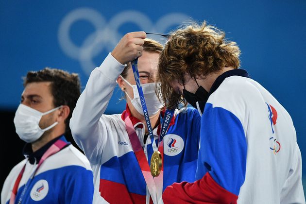 Gold medalists Anastasia Pavlyuchenkova, center, and Andrey Rublev, right, of the Russian Olympic Committee put on their respective medals during the mixed doubles tennis medal ceremony on Aug. 1.