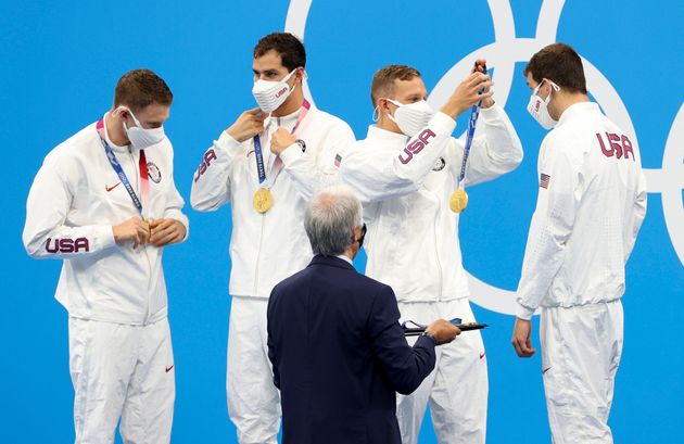 The USA's Caeleb Dressel, second from right, helps teammate Zach Apple on the podium. Dressel, Apple, Ryan Murphy (far left) and Michael Andrew (second from left) won gold in the men's 4 x 100 meter medley relay on Aug. 1.