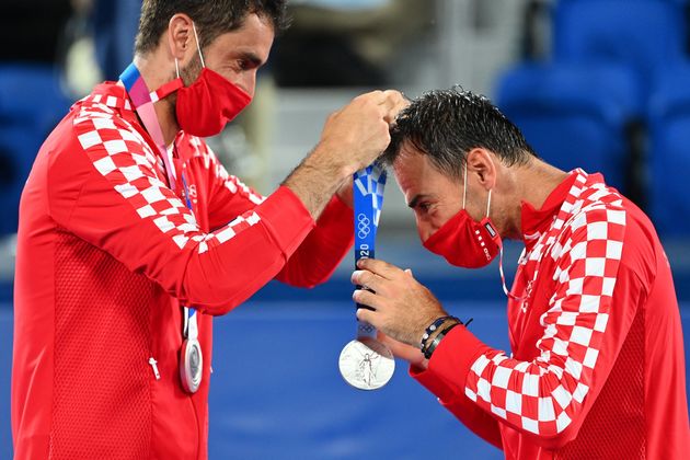 Silver medallist Marin Cilic of Croatia, left, gives Croatia's Ivan Dodig his silver medal on the podium during the men's doubles tennis ceremony at the Ariake Tennis Park in Tokyo on July 30.