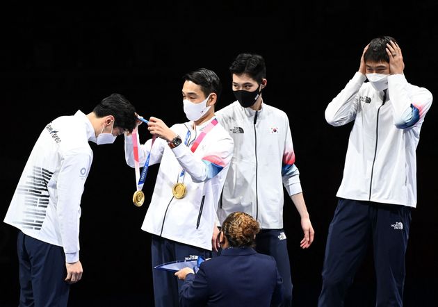 South Korea fencers receive their gold medals on the podium during the medal ceremony for the men's sabre team on July 28.
