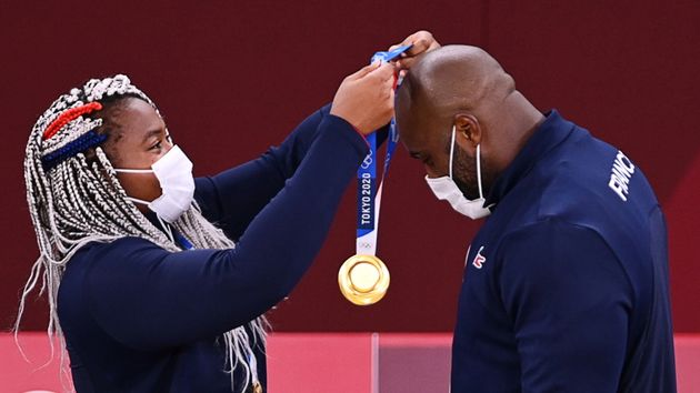Gold medalist Teddy Riner of France, right, receives a medal from teammate Romane Dicko. France won gold in the mixed team judo competition on July 31.