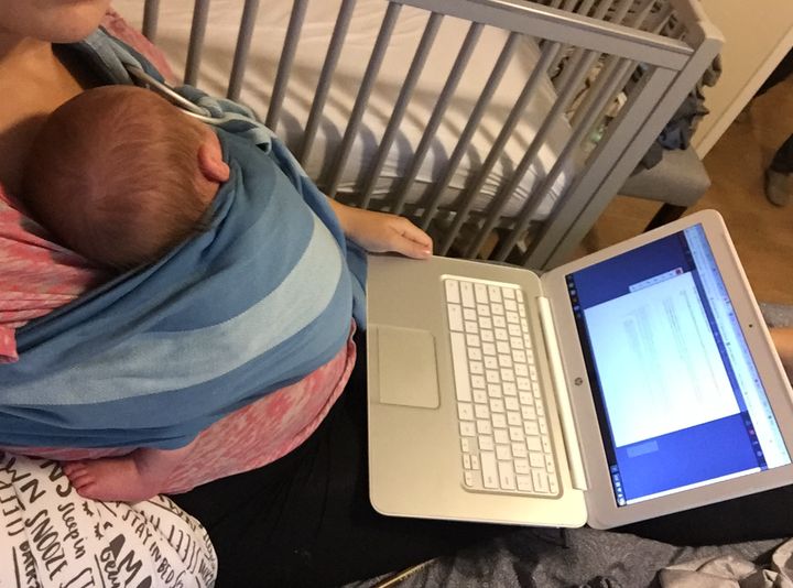 The author working while holding her second child, then 1 month old.
