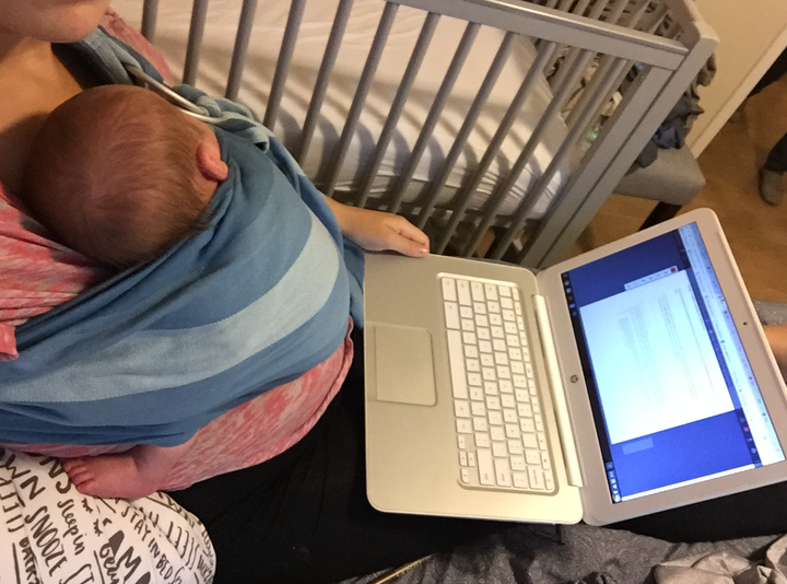 The author working while holding her second child, then 1 month old.