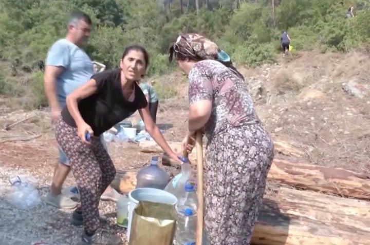 Residents tackling the local fire with water bottles despite evacuation.