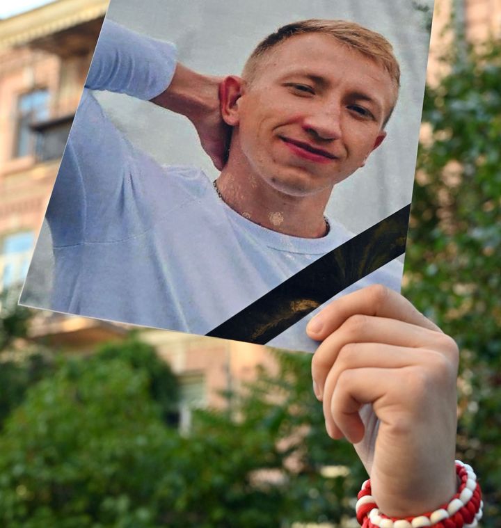 A picture of Vitaly Shishov is held by an activist as he takes part in a rally outside the Belarus embassy in Kiev on August 3, 2021. (Photo by SERGEI SUPINSKY/AFP via Getty Images)