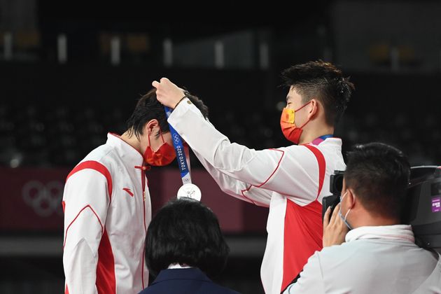 バドミントン男子ダブルスの表彰式で、銀メダルをかけ合う中国代表の李俊慧選手と劉雨辰選手。